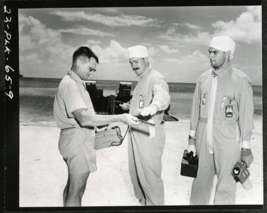 Operation Redwing Team on Bikini Atoll beach getting scanned for radiation exposure